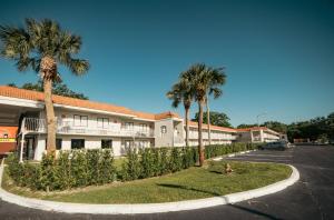 a dog sitting in front of a building with palm trees at Developer Inn Express Fundamental, a Travelodge by Wyndham in Kissimmee