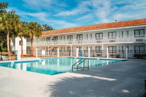 a hotel with a swimming pool in front of a building at Developer Inn Express Fundamental, a Travelodge by Wyndham in Kissimmee