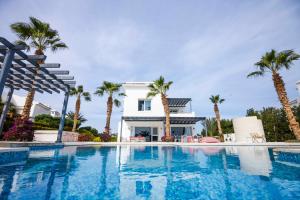 赫尔格达El Gouna Elite Worldwide Sea & Garden Residences - Hurghada, Egypt的棕榈树环绕的房子前的游泳池
