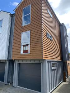 a house with a garage door and a building at Johnsonville Brand New Lovely townhouse in Wellington