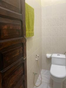 a bathroom with a toilet and a door with a hose at Caravan Serai Amour in Stone Town