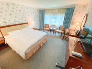 a hotel room with a large bed and a desk at Evergreen Laurel Hotel - Keelung in Keelung