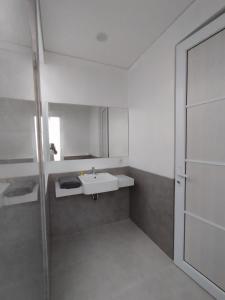 a white bathroom with a sink and a mirror at Rumah Menik in Uluwatu