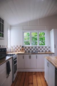 a kitchen with white cabinets and two windows at UrbanNook - Heart of the city in Brisbane