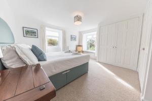 a bedroom with a large bed and two windows at Lakeland farmhouse with an acre of gardens, games room and free parking in Rusland