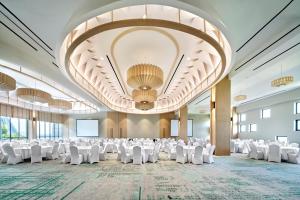 un gran salón de banquetes con mesas y sillas blancas en VIVERE Hotel, ARTOTEL Curated en Tangerang
