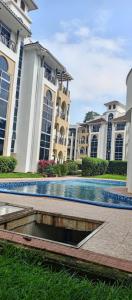 a swimming pool in front of a large building at Peninsula drive lake side apartments in Kampala