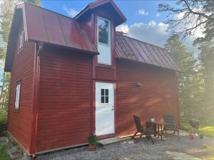 una casa roja con una puerta blanca y una mesa en Private guesthouse close to nature and the sea en Vaxholm