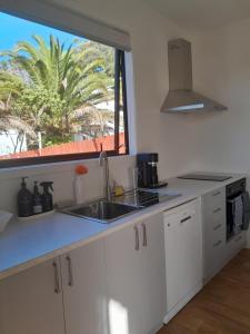 una cucina con armadi bianchi, lavandino e finestra di The Tiny Abode a Snells Beach