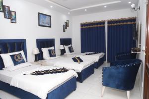três camas num quarto com azul e branco em Hotel Royal Comfort em Lahore