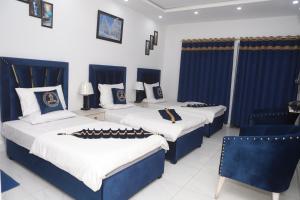 2 letti in una camera con blu e bianco di Hotel Royal Comfort a Lahore