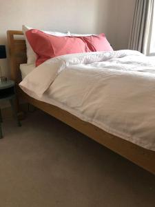 a bed with white sheets and red pillows on it at Bright, modern & close to historic town in Bishops Waltham