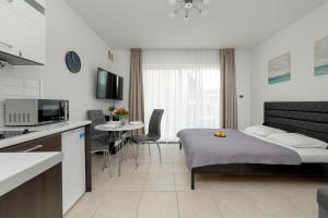 a bedroom with a bed and a kitchen with a table at White and Grey Studio with Balcony in Międzyzdroje SeaView by Rent like home in Międzyzdroje
