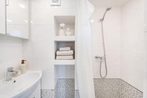 a white bathroom with a shower and a sink at Warm and light Loft near Vilnius centre in Vilnius