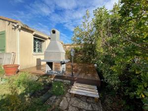 a wooden deck with a fireplace in a yard at Villa calme, terrasse, climatisée, près d'Obalia, proche mer, parking inclus, classée 3 étoiles - FR-1-503-174 in Balaruc-les-Bains +6 photos