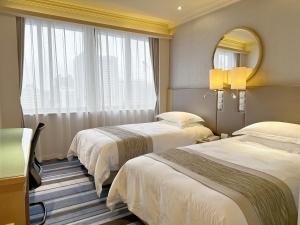 a hotel room with two beds and a mirror at Ocean Hotel Guangzhou-Free Shuttle Bus to Canton Fair in Guangzhou