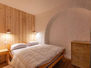 een slaapkamer met een bed en een houten muur bij Appartement Cauterets, 2 pièces, 4 personnes - FR-1-401-278 in Cauterets