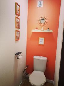 a bathroom with a toilet with an orange wall at Le Chamroussien - Appartement 1700 in Chamrousse