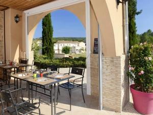 an outdoor patio with tables and chairs and an archway at Maison Salavas, 3 pièces, 4 personnes - FR-1-697-31 in Salavas