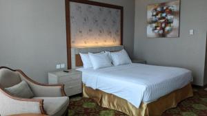 um quarto de hotel com uma cama e uma cadeira em Five Premiere Hotel em Samarinda