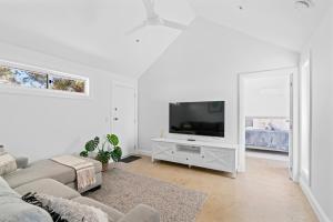 a white living room with a tv and a couch at Magnolia in Emu Bay
