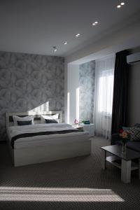 a bedroom with a large white bed and a table at Tengri Hotel in Aktau