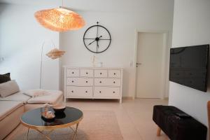 a living room with a couch and a clock on the wall at PureNature Appartement in Obersontheim