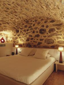 Cama en habitación con pared de piedra en La Grotte, en Corbara