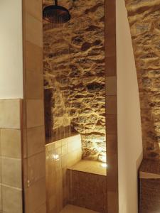 ducha en una habitación con pared de piedra en La Grotte, en Corbara