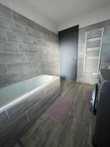 een badkamer met een bad en een houten vloer bij L'appartement du VH in Bourg-en-Bresse