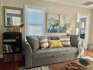 Una sala de estar con un sofá gris con almohadas. en New, Modern, 3 bed/3 bath Apt, 10 miles to DC!, en Falls Church
