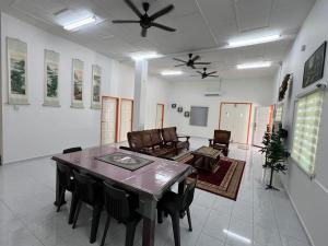 Agro Village Stay في Tapah: غرفة معيشة مع طاولة طعام وكراسي