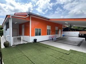 Agro Village Stay في Tapah: منزل برتقالي مع كراسي على الفناء