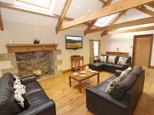 a living room with leather furniture and a stone fireplace at 3 Bed in Northumberland National Park CN043 in Alwinton