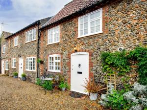 an old stone house with a white door at 2 Bed in Holt NCC14 in Holt