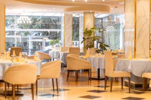 un ristorante con tavoli e sedie bianchi e finestre di Bonanza Addis Hotel ad Addis Abeba