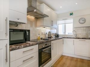a kitchen with white cabinets and a stove top oven at 4 Bed in Brixham BX072 in Brixham