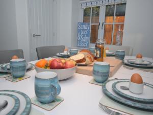 a table with plates and eggs and a bowl of fruit at 3 Bed in Cromer 47832 in Northrepps