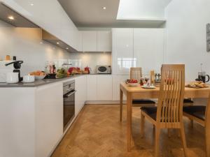 a kitchen with white cabinets and a wooden table and chairs at 1 Bed in Spark Bridge LCC52 in Spark Bridge