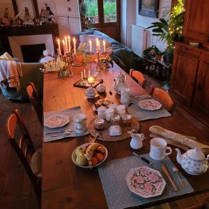 einen Tisch mit Kerzen und Teller mit Essen drauf in der Unterkunft Le Béarn sous les toits in Nay