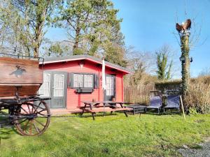 ein rotes winziges Haus mit einem Picknicktisch und einem Wagen in der Unterkunft Chalet Opale Texas in Hermelinghen