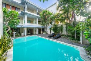 an apartment with a swimming pool in front of a building at Spazzio Bali Hotel in Legian