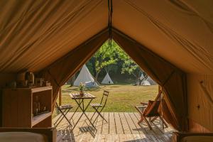 Ca Stella Camping del Monte San Giorgio في Meride: خيمة مع طاولة وكراسي وخيام