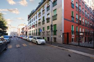 una fila di auto parcheggiate in una strada accanto agli edifici di PrimoPiano - Arrivabene a Milano