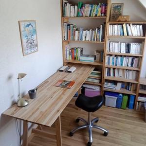 uma secretária com uma cadeira e uma estante de livros com livros em Maison au calme, dans le village d'Erdeven em Erdeven