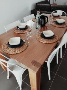 - une table à manger en bois avec des chaises blanches, des assiettes et des verres dans l'établissement Comme à la maison, à Sainte-Hélène