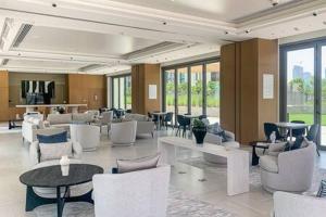 a lobby with white chairs and tables and windows at Frank Porter - Downtown Views II T3 in Dubai