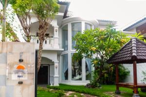 Private Urban Villa Denpasar في دينباسار: البيت الأبيض مع شرفة أمامه