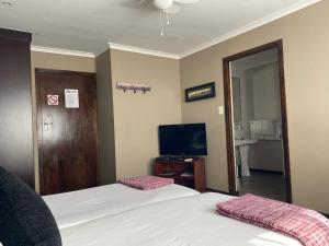 um quarto de hotel com duas camas e uma televisão em Olaf's Guest House "Solar installed" em Cidade do Cabo