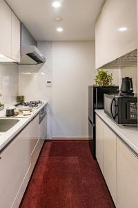 a kitchen with white cabinets and a black microwave at Apartment Hotel 11 Shinsaibashi in Osaka